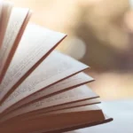 An open book resting on a table, featuring a softly blurred background, associated with MyDearQuotes.com Blog.