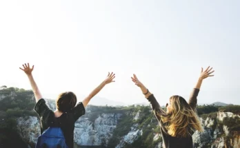 Two women raise their arms in the air, expressing excitement after realizing the traveler hired the wrong tour guide.