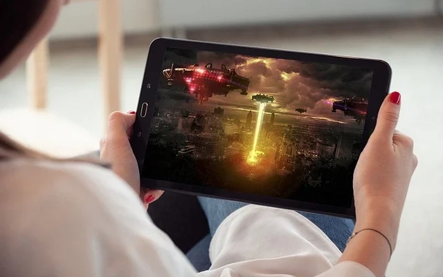 A woman engaged with a tablet, immersed in a m4umovies, showcasing her enjoyment of digital entertainment.