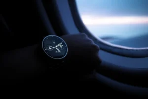 An individual seated on an airplane, sporting a Porsamo Bleu watch review, highlighting the blend of travel and sophistication.