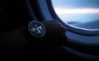 An individual seated on an airplane, sporting a Porsamo Bleu watch review, highlighting the blend of travel and sophistication.