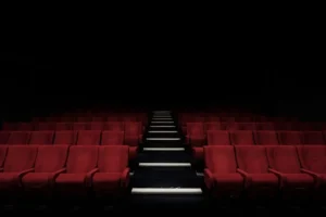 A view of vacant cinema seats against a dark backdrop in Tulare Luxury Theater, evoking a sense of calm and anticipation.
