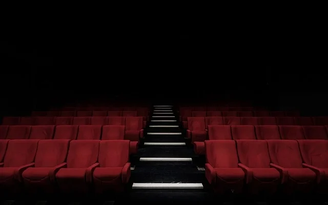 A view of vacant cinema seats against a dark backdrop in Tulare Luxury Theater, evoking a sense of calm and anticipation.