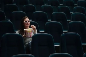 A woman relaxes in a century luxury cinemas, savoring popcorn as she prepares to enjoy a film in an elegant setting.