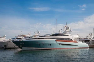 A group of various M/Y Kasper 7 docked in a marina, some sailing on the water under a clear sky with a few clouds. The scene showcases different types of watercraft including yachts and speedboats.