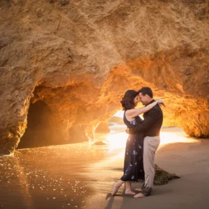 Couple standing in front of a cave at sunset, captured during an engagement shoot at El Matador State Beach.