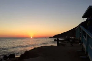 Sunset over the ocean at Las Tunas Beach, with a lifeguard tower silhouetted against the vibrant sky.