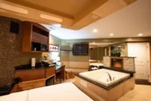 A luxurious hotel room at The Champagne Lodge featuring a jacuzzi tub and a television for relaxation and entertainment.