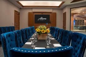 A conference room featuring blue velvet chairs and a large screen, set in the Ahern luxury boutique hotel dining area.