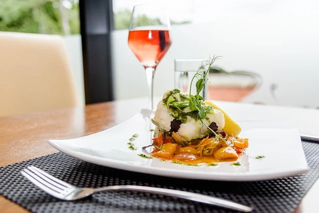 A white plate with gourmet food and a glass of rosé wine, set at Rose's Luxury D.C in Washington.