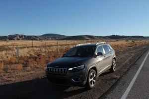 A 2019 Jeep Cherokee parked on the roadside, showcasing its sleek design among unsold luxury SUVs like the Buick Envision.