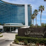 Fairmont Century Plaza luxury hotel exterior in Los Angeles with palm trees, fountain, and landscaped entrance.