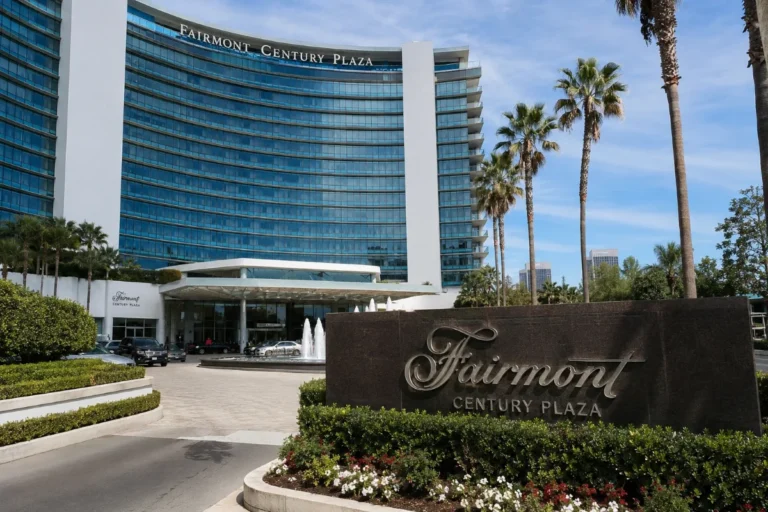 Fairmont Century Plaza luxury hotel exterior in Los Angeles with palm trees, fountain, and landscaped entrance.