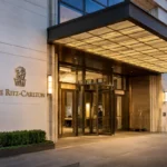 The Ritz-Carlton luxury hotel entrance with elegant architecture, warm lighting, glass doors, and landscaped surroundings at dusk.