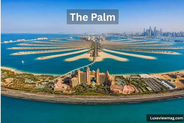 Aerial view of The Palm in Dubai, showing its palm-shaped island, turquoise waters, luxury resort, villas, and Dubai skyline.