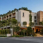 1 Hotel West Hollywood in Los Angeles, featuring lush greenery, modern natural-wood architecture, landscaped terraces, and a warmly lit entrance along Sunset Boulevard.