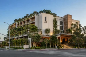 1 Hotel West Hollywood in Los Angeles, featuring lush greenery, modern natural-wood architecture, landscaped terraces, and a warmly lit entrance along Sunset Boulevard.