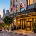 Omni San Francisco Hotel exterior entrance at dusk with a San Francisco cable car and city skyline in the background.