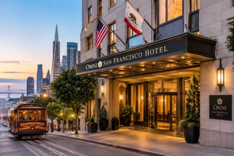 Omni San Francisco Hotel exterior entrance at dusk with a San Francisco cable car and city skyline in the background.