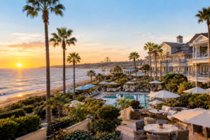 L'Auberge Del Mar luxury coastal hotel overlooking the Pacific Ocean with a swimming pool and palm trees in Del Mar, California.